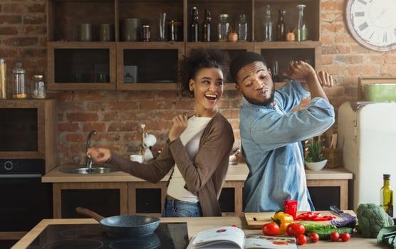 Black couple dancing near table with food in kitchen. Family having fun while cooking photo