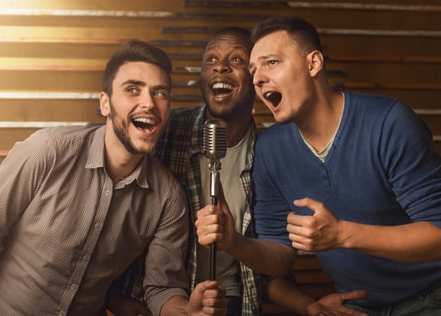 Happy male friends singing karaoke together in bar photo