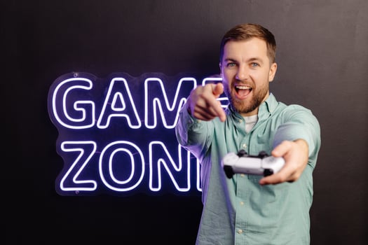 Young bearded man standing at the wall in the room and playing, holding wireless joystick, screaming, and winning intense game match photo