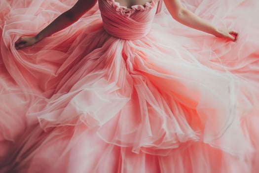 A person in a soft pink gown twirls gracefully, surrounded by layers of flowing fabric. The gentle light creates a dreamy atmosphere, enhancing the gown's delicate features photo