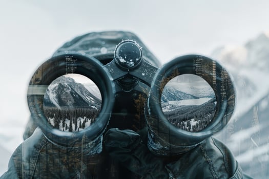 A person looking through binoculars with mountains in the background photo