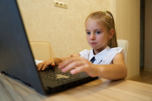 Young girl focused on laptop while studying in a cozy indoor space photo