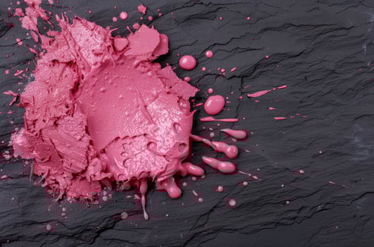 Splattered pink makeup on dark slate background photo