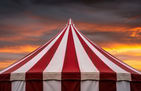 Vibrant circus tent against a dramatic sunset sky photo