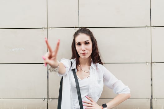 Young woman shows peace sign in urban setting during daytime photo