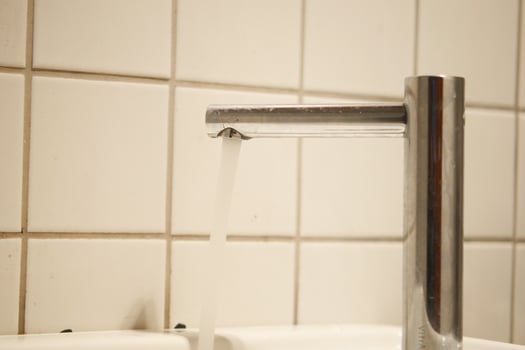 A contemporary faucet with water cascading effortlessly in a pristine, welcoming bathroom space photo