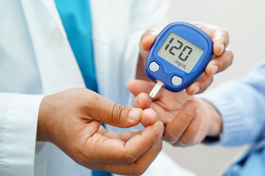 Asian doctor using digital glucose meter for check sample blood sugar level to treatment diabetes. photo