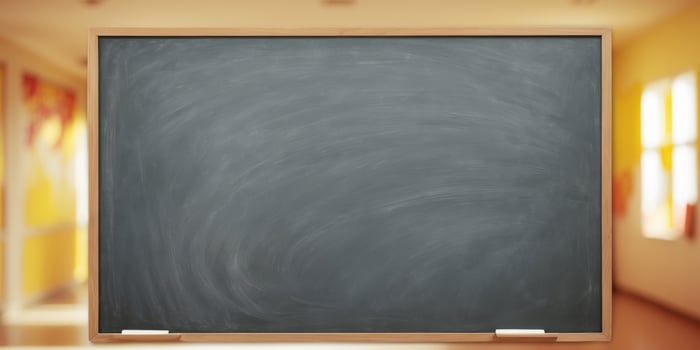 A blackboard in front of a classroom with a bright yellow wall photo