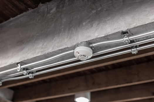 Smoke detector, fire alarm detector indoor home safety device with IMC metal pipeline at ceiling photo