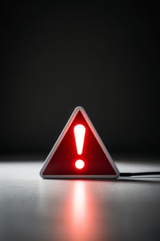 glowing neon red triangle sign with exclamation point on dark warning indicator alert signal. photo
