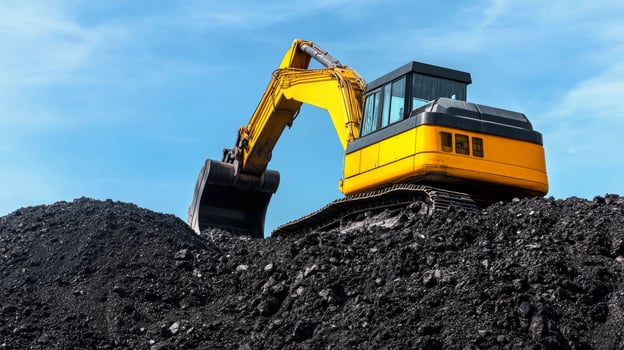 Heavy machinery transports coal at a mining site under a clear blue sky photo