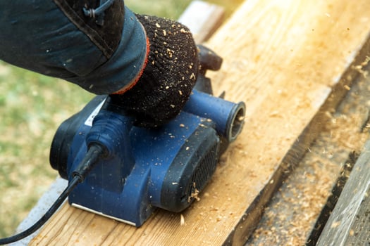 A man works with an electric tool with an electric planer, cleans old wood. Industry, close-up photo