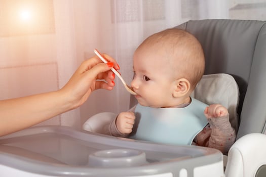 Mother feeds baby boy vegetable puree from a spoon. Feeding children 7 months. Close-up. Copy space for text photo