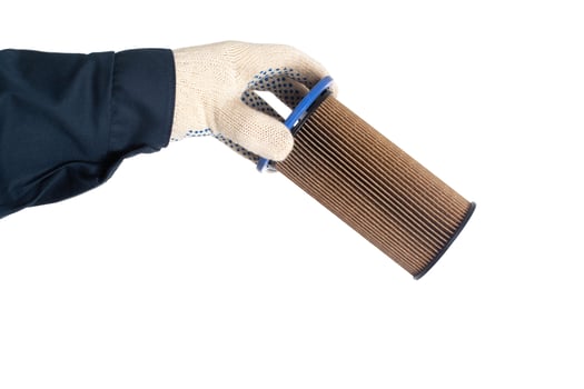 An auto mechanic holds an old dirty fuel filter in his hand. Fuel filter replacement concept, low-quality fuel, white background, isolate photo