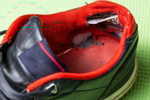 A ripped backdrop in sporty multicolored sneakers. Poor quality shoes, close-up photo