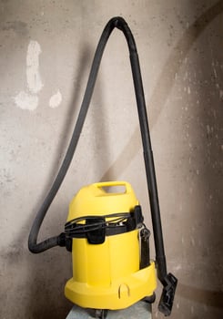 Industrial vacuum cleaner for cleaning construction debris on the background of a concrete wall, close-up photo