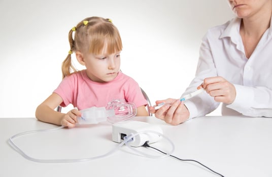 A doctor is putting a drug into a nebulizer for the treatment of respiratory diseases in a little girl 5 years old. Inhalation for the treatment of bronchitis and pneumonia photo