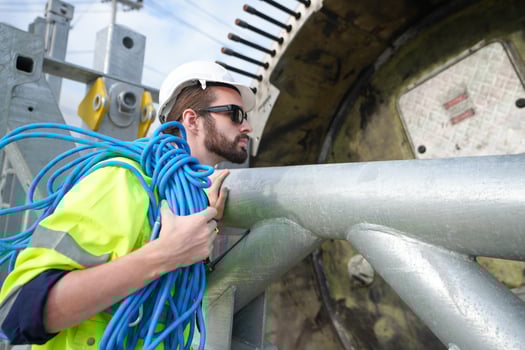 A man in a safety vest is holding a blue cable photo