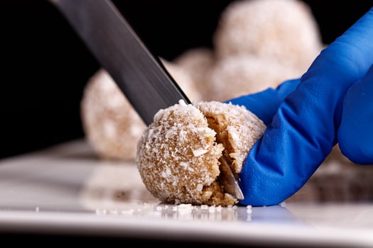 Beautiful sweets with coconut are cut with a knife on a white plate on a black background photo