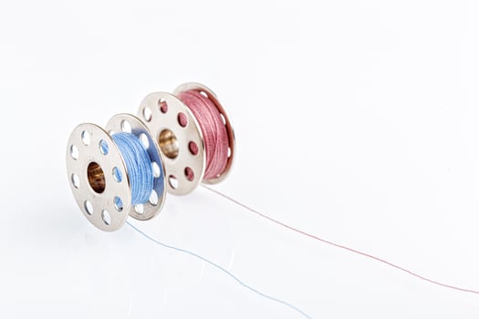 spools of blue and pink thread on a white background photo
