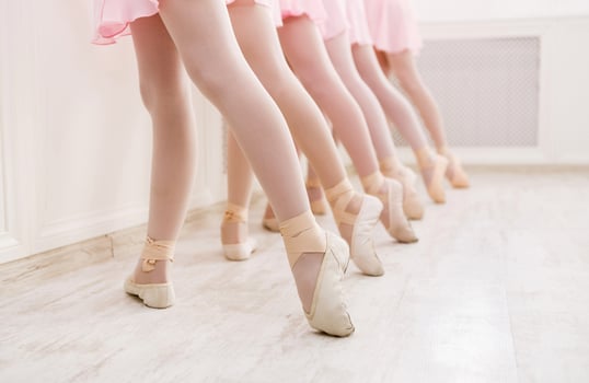 Ballet background, young ballerinas training. Little dancers legs in pointe shoes, making exercises. Classical dance school, copy space photo