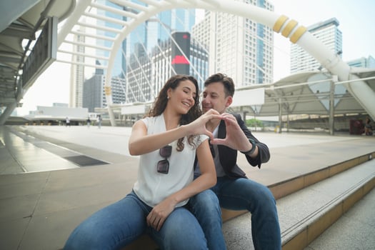 A man and woman sitting on a bench in front of a city building photo