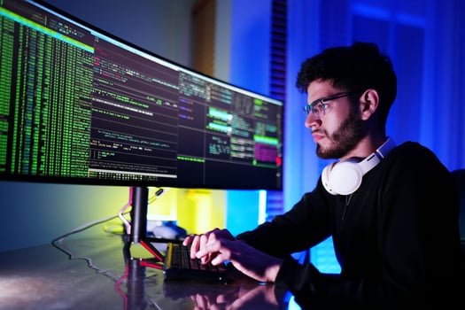 A man in black shirt and headphones working on a computer photo