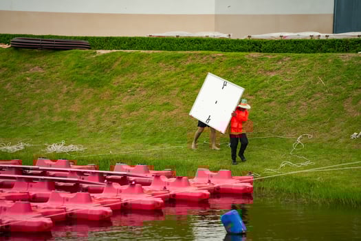 A man is carrying a large white board onto a boat photo