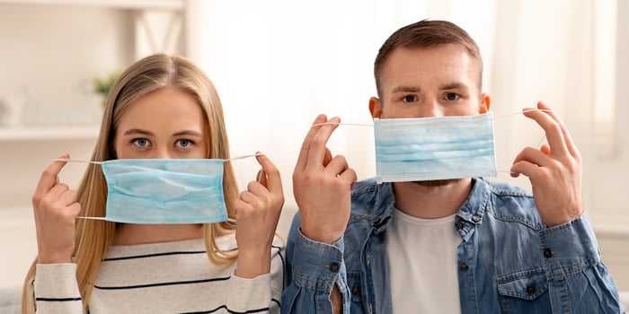 Coronavirus prevention. Young couple putting on protective medical masks at home photo