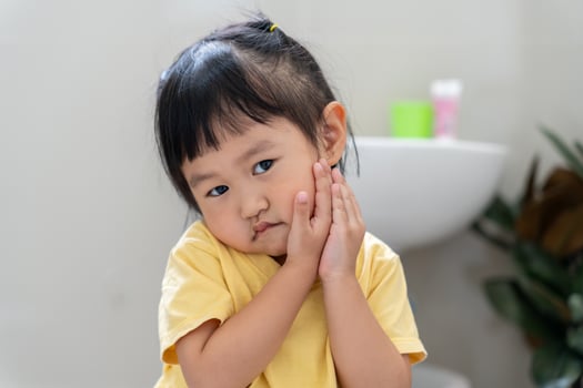 little asian girl presses hand to cheek, suffers from pain in tooth. Teeth decay, dental problems, child emotions and facial expression, oral health care, reducing sweets, fluorine coating photo