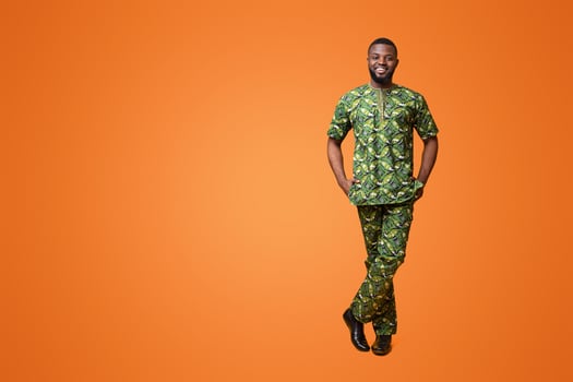 Handsome black man in traditional african green clothes posing over yellow studio background photo