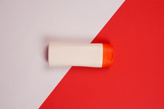 Plastic shampoo bottle with flip-top lid isolated on red and white background. MockUp template for your design. Empty and clean packaging for cosmetic product. File contains clipping path. photo