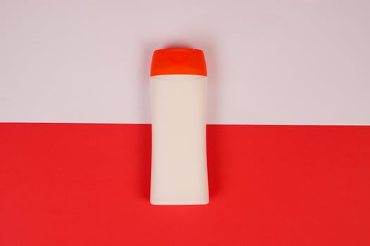 Plastic shampoo bottle with flip-top lid isolated on red and white background. MockUp template for your design. Empty and clean packaging for cosmetic product. File contains clipping path. photo