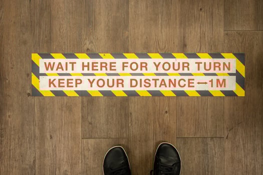 Wait your turn, keep your distance sign on a store floor. photo