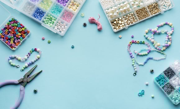 Colorful assortment of beads and jewelry-making tools on a blue surface with completed bracelets photo