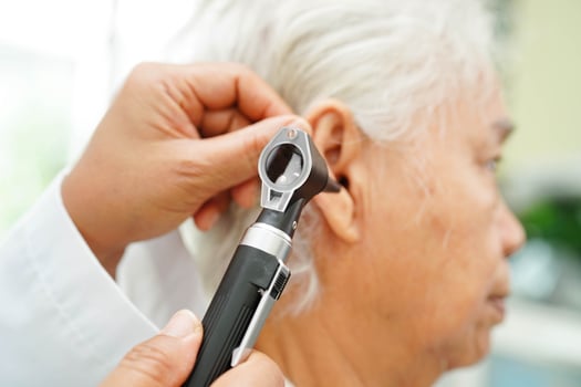 Otolaryngologist or ENT physician doctor examining senior patient ear with otoscope, hearing loss problem. photo