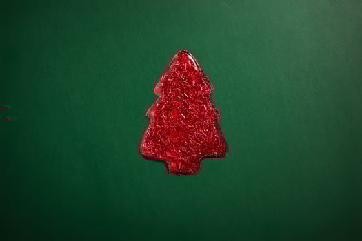 red sparkly jelly shaped like a Christmas tree on green background. Minimalistic holiday photo