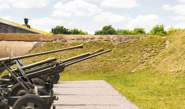Military guns installed on the street against the backdrop of a bomb shelter. Military conflict, aggression. Copy space for text photo