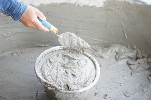 Close up worker hand hold a trowel to mix wet cement in bucket. Concept. Construction job. Process of construction work with cement. Choose good quality and proper material product for building photo
