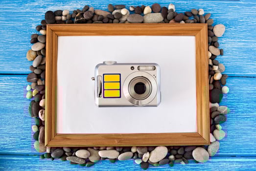 Clean frame on a blue wooden background, seashells and camera photo