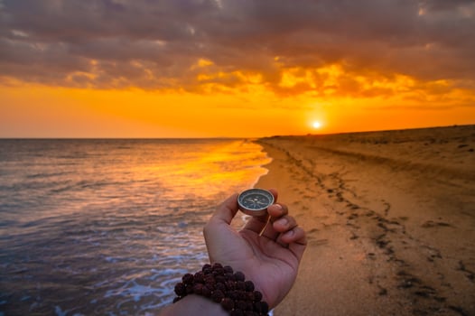 First person view of a man's hand holding a compass against a beautiful seascape. Navigation concept of finding your own way and orientation to the cardinal points photo