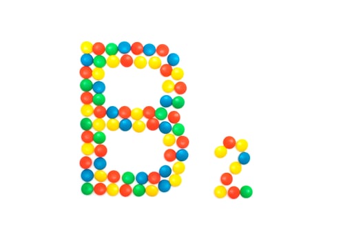 Multi-colored vitamins pills that are lined with the letter Vitamin group B2, close-up photo
