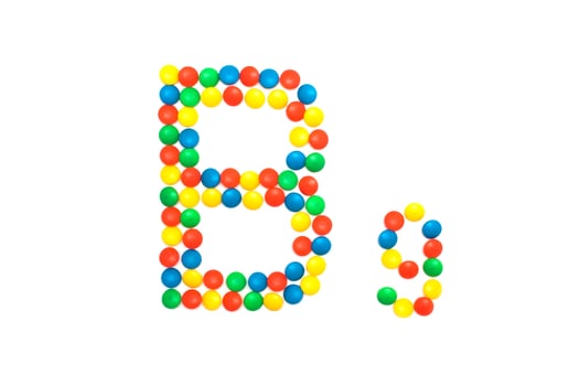 Multi-colored vitamins pills that are lined with the letter Vitamin group B9, close-up photo