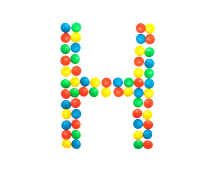 Multi-colored vitamins pills that are lined with the letter Vitamin H, close-up photo