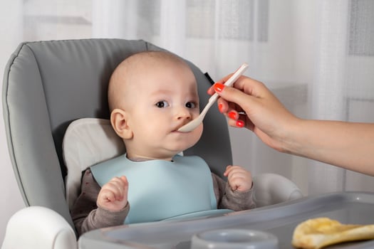 Mother feeds baby boy vegetable puree from a spoon. Feeding children 7 months. Close-up photo