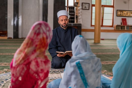 A Muslim teacher teaches child girl to read a holy book Quran inside the Mosque. photo