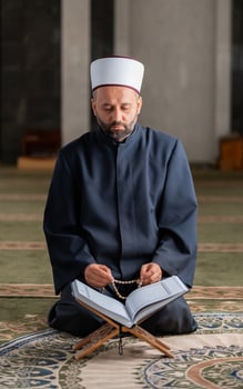 A Muslim prayer man praying while reading a Quran inside the mosque. photo