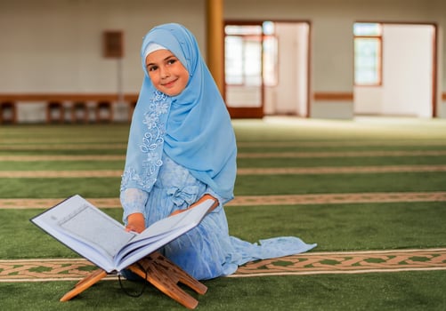 A Muslim child girl reading a Quran inside the mosque. photo