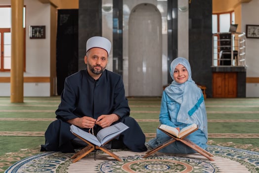 A Muslim teacher teaches child girl to read a holy book Quran inside the Mosque. photo