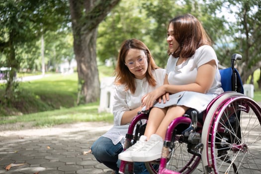 Young Woman in Wheelchair Enjoying a Day in the Park with Her Best Friend on a Sunny Afternoon photo